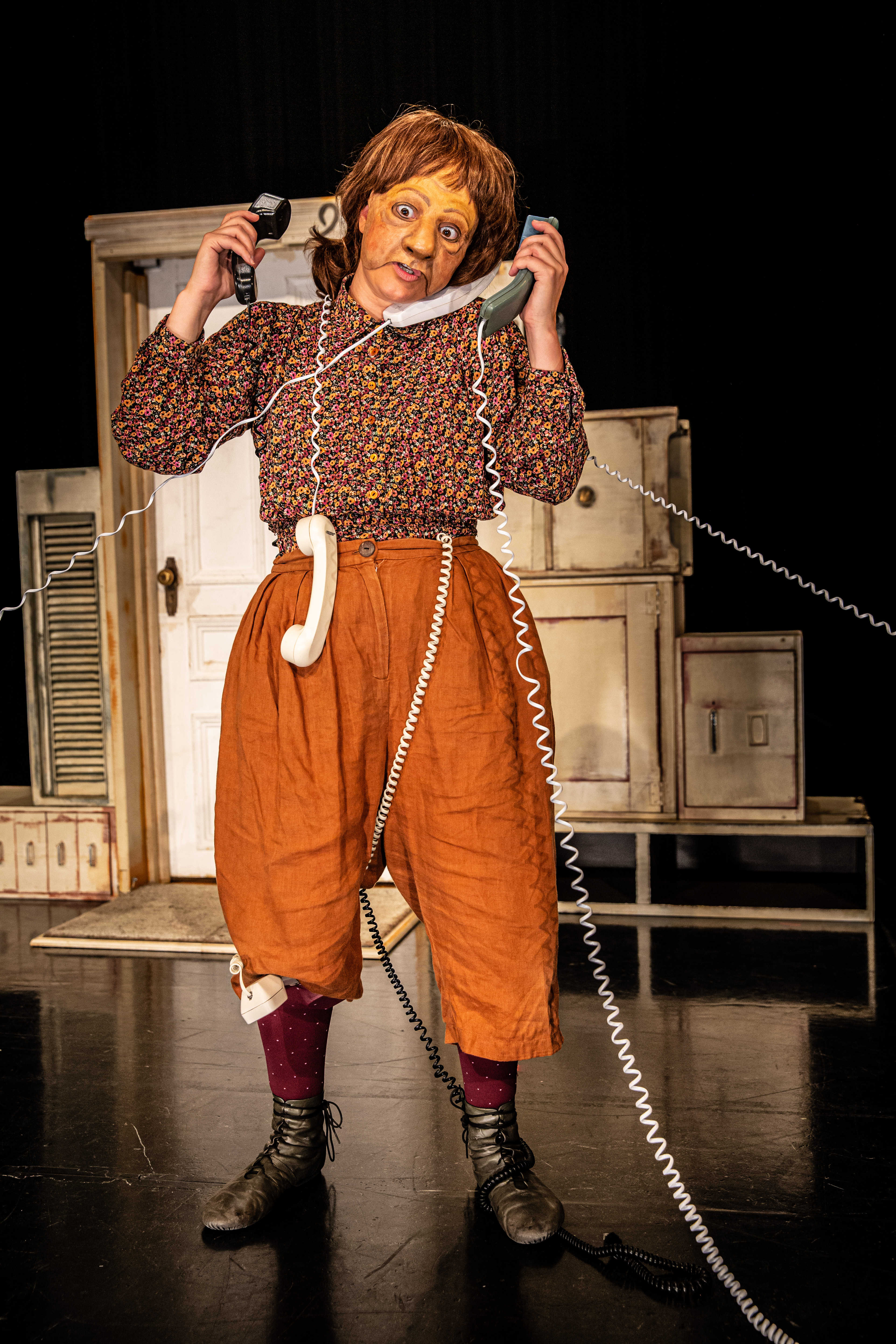 brielle-spectacle.jpg Brielle - Personne sur scène tenant plusieurs combinés téléphoniques avec des fils torsadés.