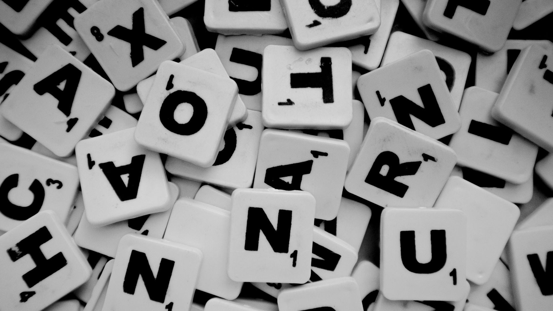 Tas de tuiles de Scrabble blanches éparpillées, illustrant le jeu Scrabble Duplicate.