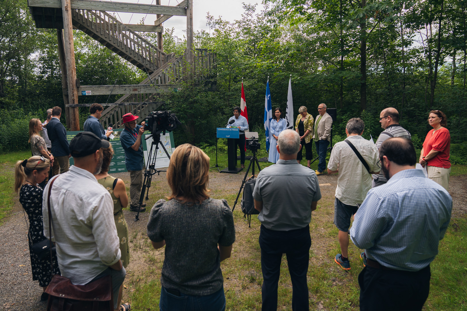 Julie Bourdon mairesse de Granby, derrière un lutrin bleu portant l’inscription “Conférence de presse Granby”, en extérieur, avec des drapeaux du Québec et du Canada en arrière-plan, lors de la présentation de la Stratégie pour un avenir vert et durable.