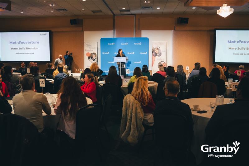 Conférence à Granby avec une allocution d’ouverture devant un public assis à des tables rondes, deux écrans affichant le titre de la présentation et un podium avec le logo Granby.