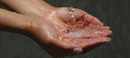 De l'eau tombe dans les mains d'une personne