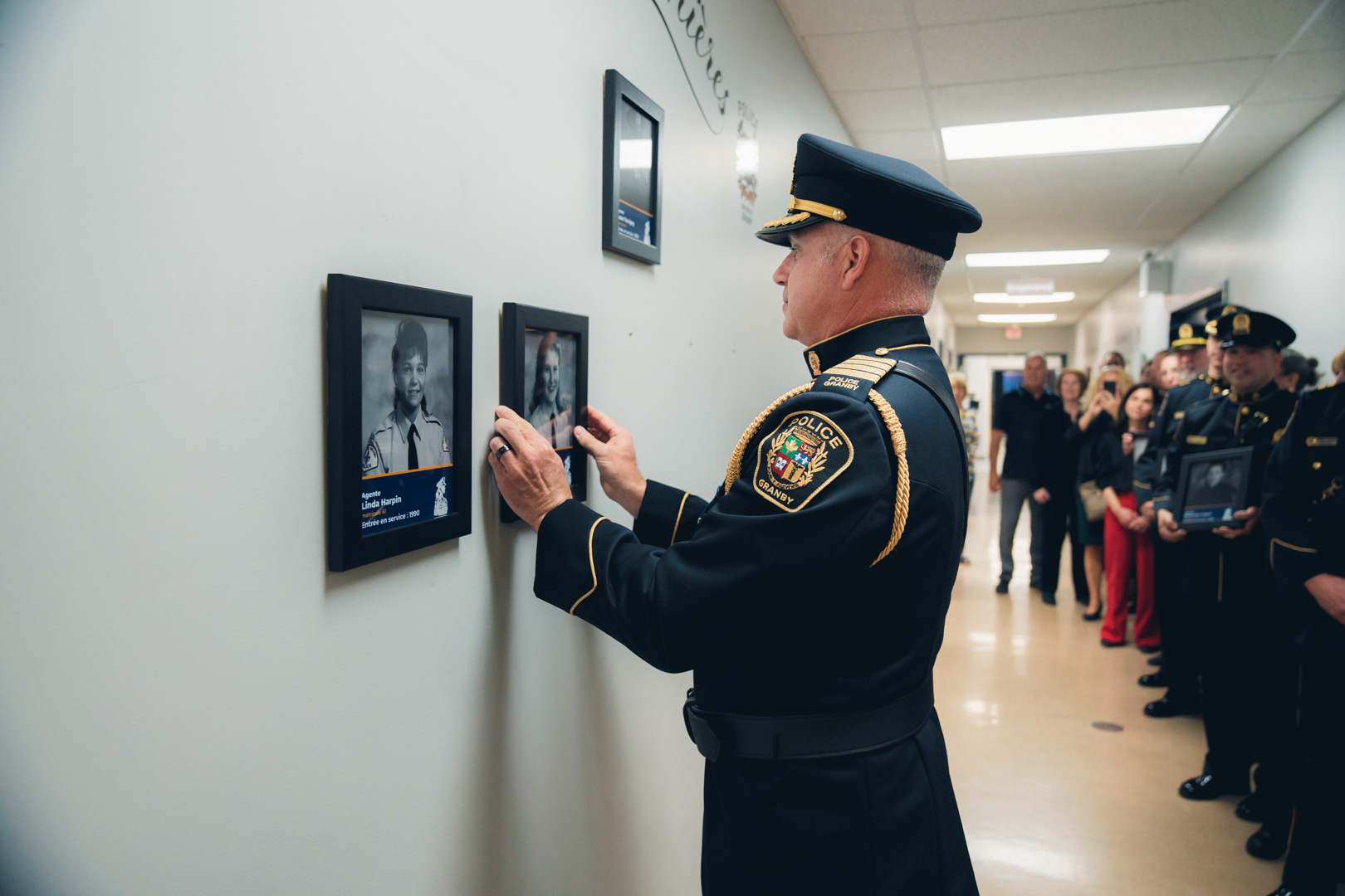 Policier en uniforme accrochant un cadre photo au mur lors d’une cérémonie d’hommage.