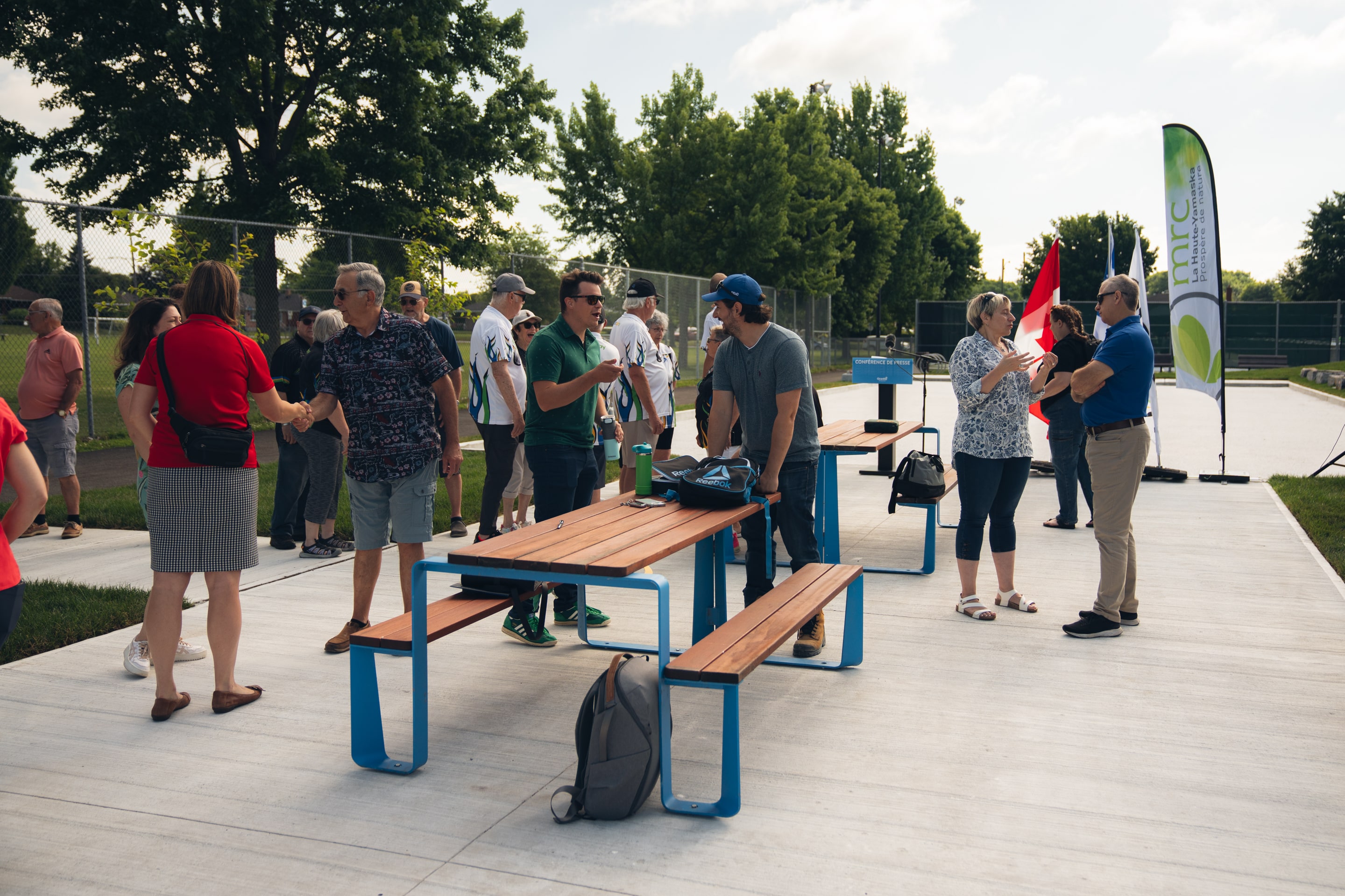 Groupe de personnes sur un terrain de pétanque au parc Dubuc, avec plusieurs boules disposées au sol, lors de l’ouverture officielle des nouveaux terrains de pétanque à Granby.