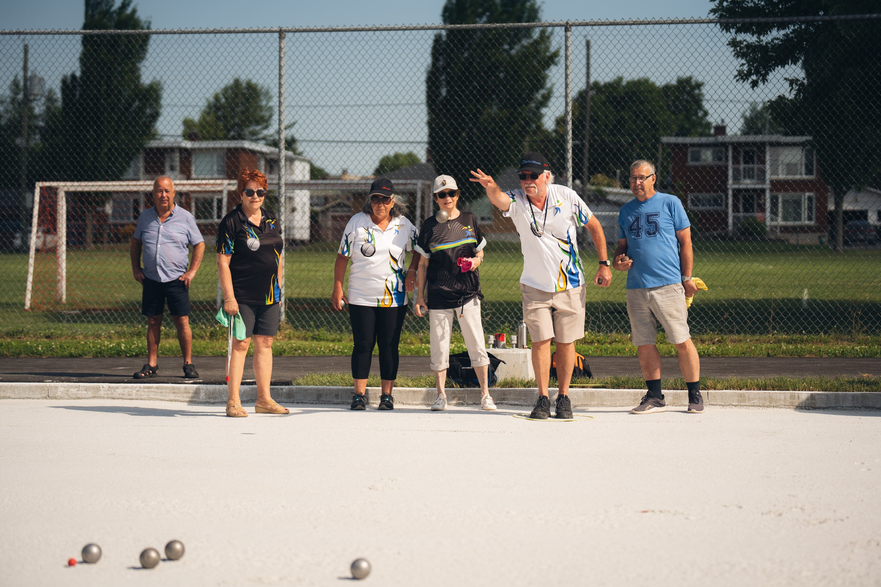 Julie Bourdon mairesse de Granby avec un groupe de personnes sur un terrain de pétanque au parc Dubuc, avec plusieurs boules disposées au sol, lors de l’ouverture officielle des nouveaux terrains de pétanque à Granby.