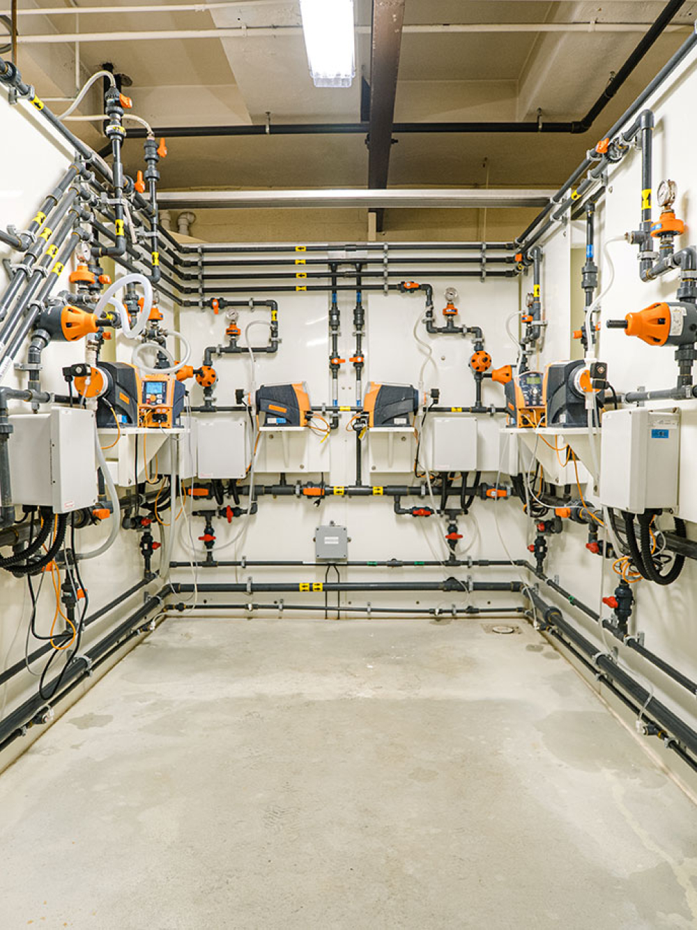 Salle technique avec plusieurs conduites, pompes et équipements de traitement.