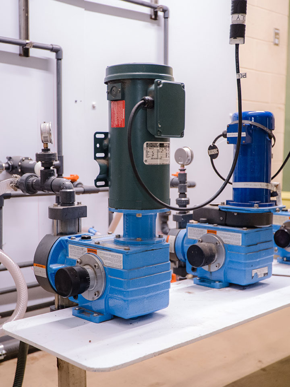 Trois pompes industrielles bleues installées sur une table dans une salle technique.