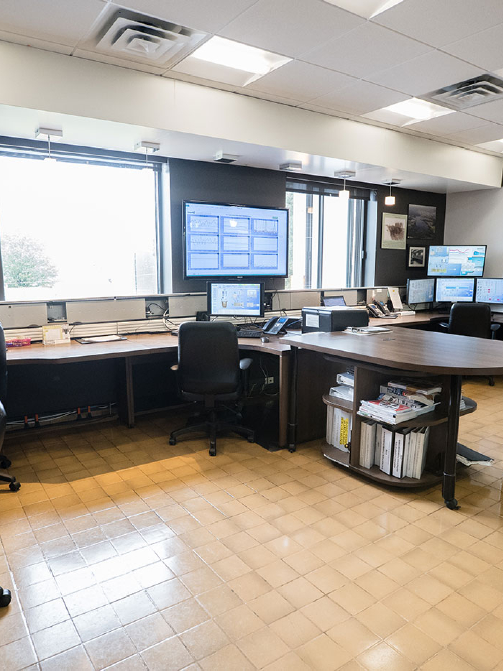 Salle de contrôle avec plusieurs postes de travail et écrans de surveillance.